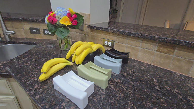 Multiple Banana Vases on a kitchen counter with bananas and flowers
